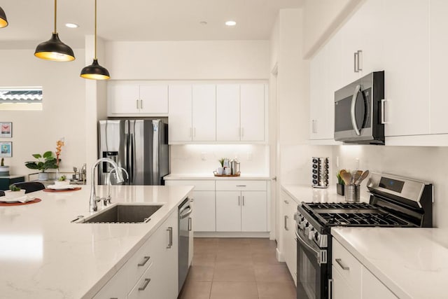 kitchen featuring hanging light fixtures, white cabinets, sink, and stainless steel appliances