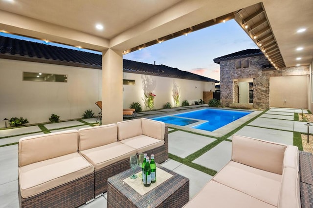 pool at dusk with a patio area and an outdoor living space