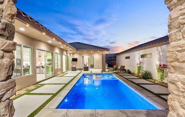 pool at dusk with a patio area