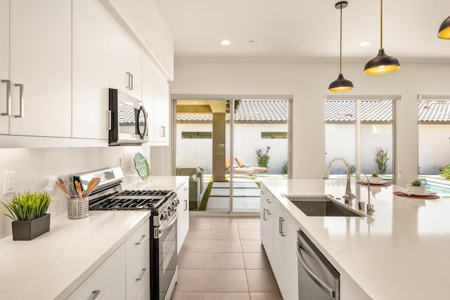 kitchen featuring appliances with stainless steel finishes, white cabinets, decorative light fixtures, and sink