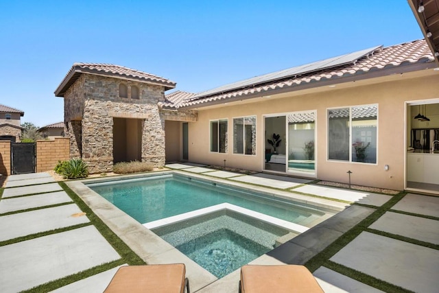 back of house with a swimming pool with hot tub, a patio area, and solar panels