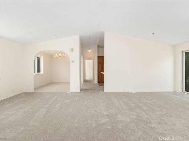 carpeted empty room featuring a chandelier