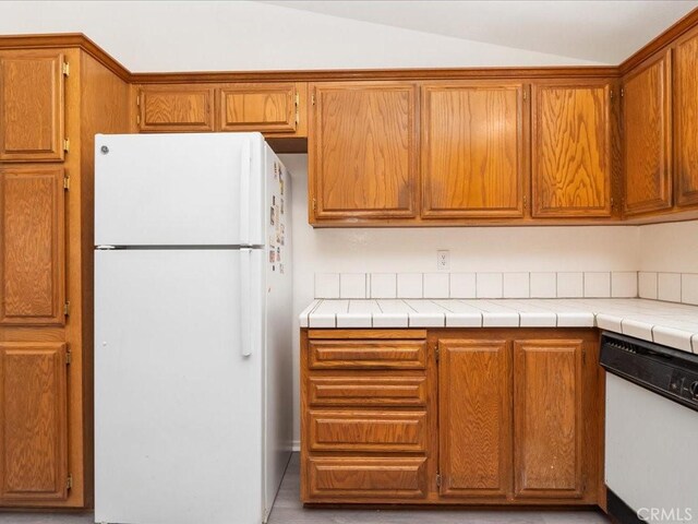 kitchen with tile countertops, lofted ceiling, and white appliances