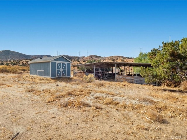 view of horse barn featuring a mountain view and a rural view