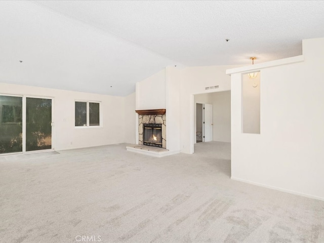 unfurnished living room with light colored carpet, vaulted ceiling, a fireplace, and a textured ceiling