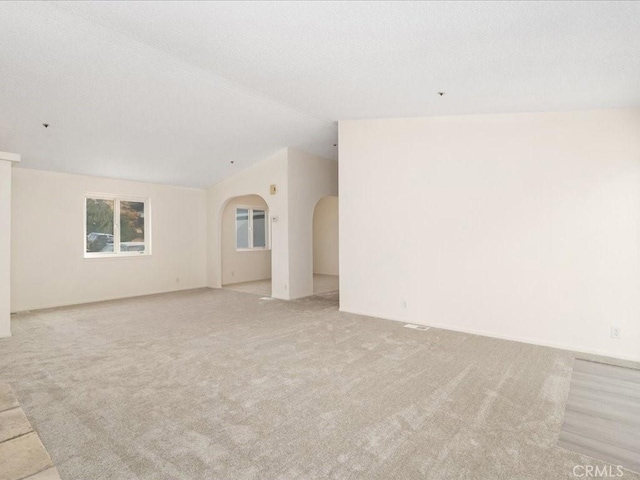 empty room featuring a textured ceiling and lofted ceiling