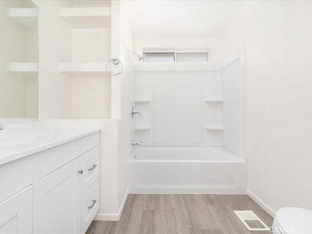 full bathroom with toilet, vanity, wood-type flooring, and washtub / shower combination