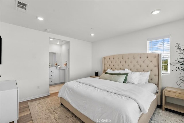 bedroom with ensuite bathroom and wood-type flooring