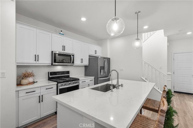 kitchen featuring sink, white cabinetry, hanging light fixtures, a kitchen island with sink, and stainless steel appliances