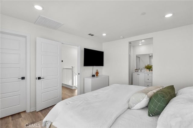 bedroom with light wood-type flooring and connected bathroom