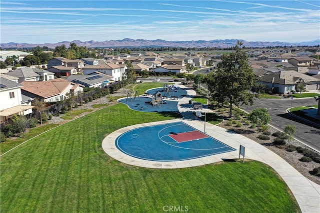 exterior space featuring a mountain view, a lawn, and basketball hoop