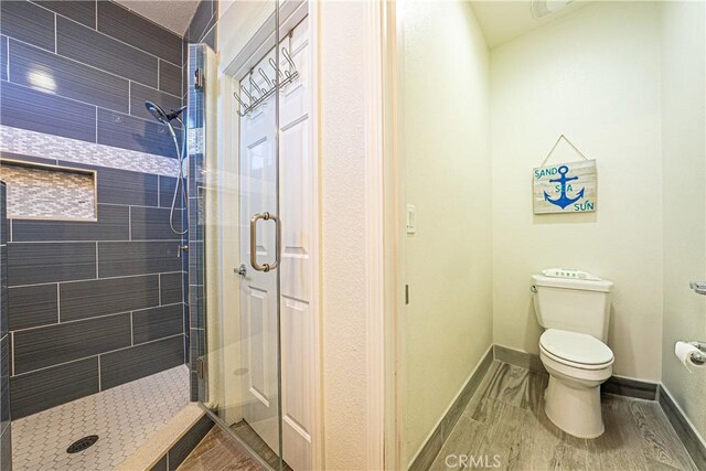 bathroom featuring toilet, wood-type flooring, and a shower with shower door