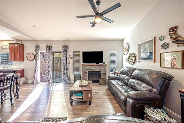 living room featuring ceiling fan, light hardwood / wood-style floors, a fireplace, and sink