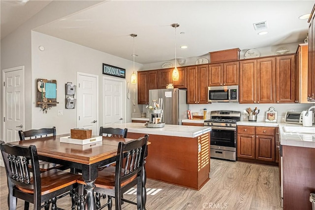 kitchen featuring light hardwood / wood-style floors, appliances with stainless steel finishes, lofted ceiling, hanging light fixtures, and a center island