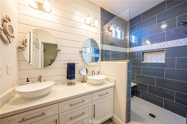 bathroom featuring a tile shower, wood walls, and vanity