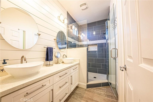 bathroom featuring a shower with shower door, wood walls, and vanity