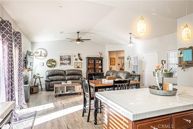 kitchen featuring tile countertops, ceiling fan, light wood-type flooring, lofted ceiling, and pendant lighting