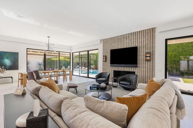 living room with an inviting chandelier, a wealth of natural light, and a large fireplace