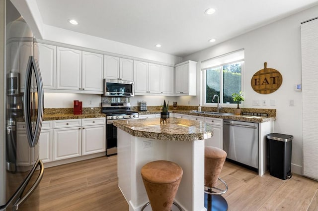 kitchen featuring sink, appliances with stainless steel finishes, a center island, white cabinets, and light wood-type flooring