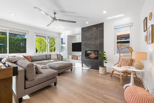 living room with ceiling fan, a fireplace, and light hardwood / wood-style floors