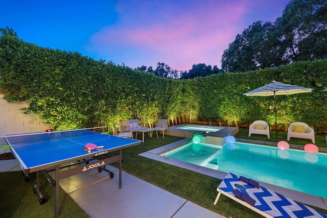 pool at dusk with an in ground hot tub