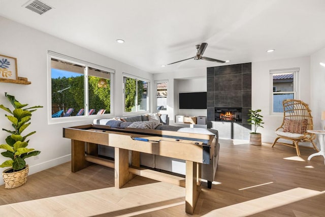 living room with ceiling fan, a fireplace, and light wood-type flooring