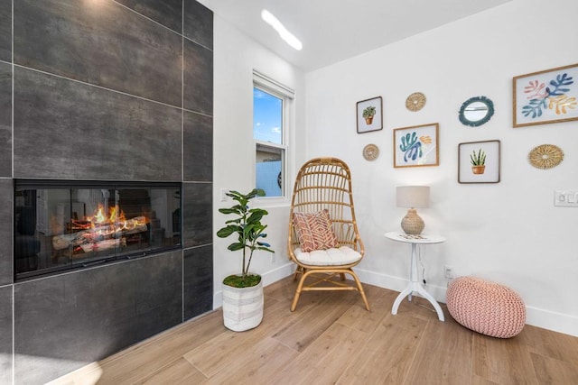 living area featuring hardwood / wood-style flooring and a tiled fireplace