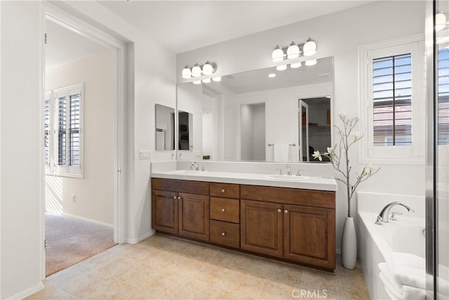 bathroom with vanity, tile patterned flooring, plenty of natural light, and tiled tub