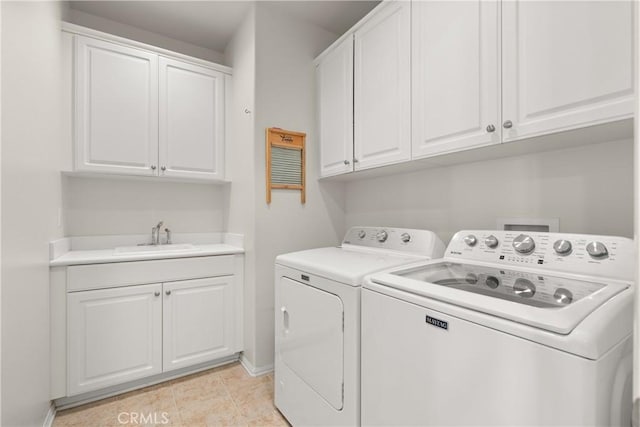 clothes washing area with cabinets, washing machine and clothes dryer, and sink