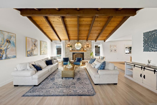 living room featuring beamed ceiling, a stone fireplace, light hardwood / wood-style flooring, and wooden ceiling