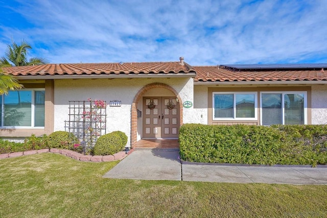 view of exterior entry with french doors, a yard, and solar panels