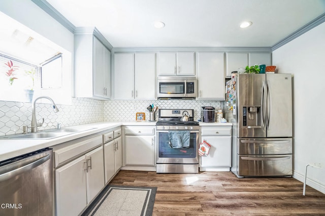 kitchen featuring sink, crown molding, white cabinetry, dark wood-type flooring, and appliances with stainless steel finishes