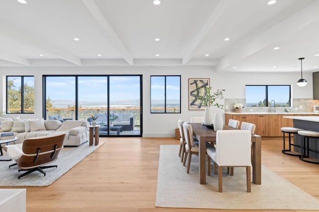 dining room with beam ceiling, light hardwood / wood-style flooring, and sink