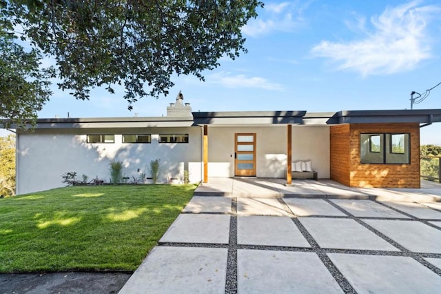 contemporary home with a front lawn and a patio area