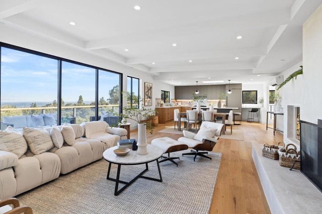 living room featuring a wall mounted air conditioner, beam ceiling, and light hardwood / wood-style flooring