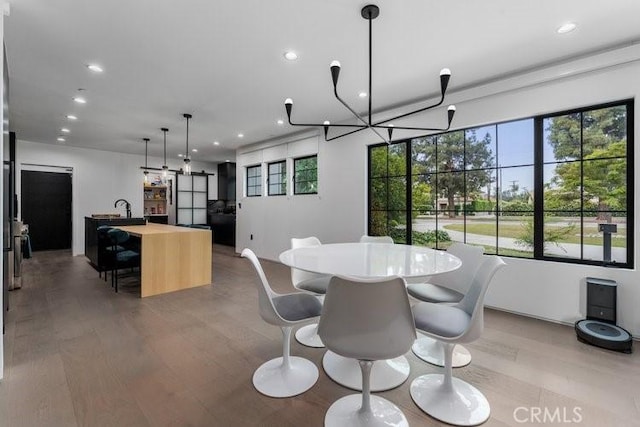 dining area featuring sink, light hardwood / wood-style flooring, and a notable chandelier