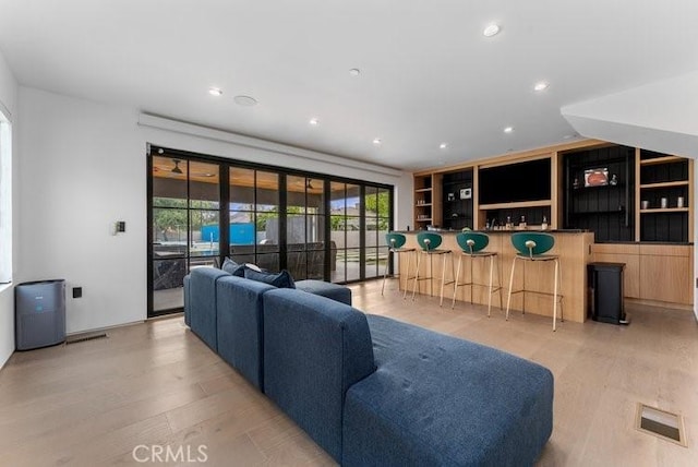 living room with light hardwood / wood-style floors and bar area