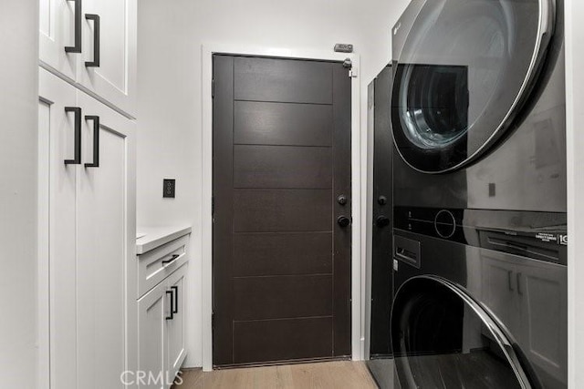 clothes washing area with stacked washer / dryer and light wood-type flooring