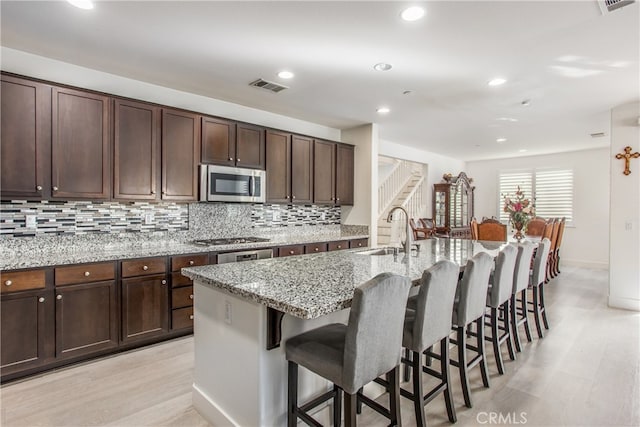 kitchen featuring light stone countertops, sink, appliances with stainless steel finishes, and a kitchen island with sink