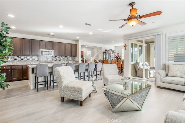 living room with ceiling fan and light hardwood / wood-style floors