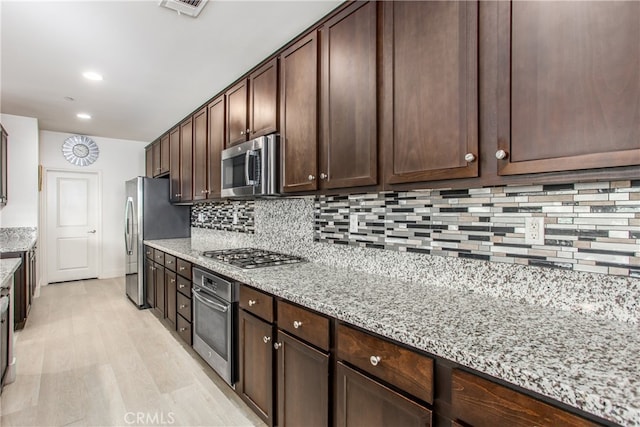 kitchen featuring decorative backsplash, light hardwood / wood-style flooring, light stone countertops, stainless steel appliances, and dark brown cabinets