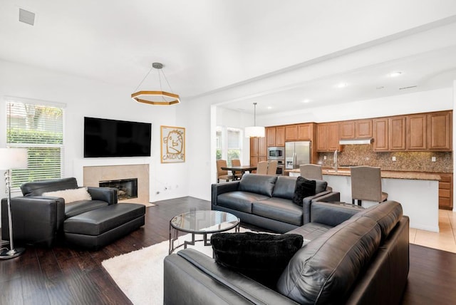 living room with dark wood-type flooring, a tiled fireplace, and sink