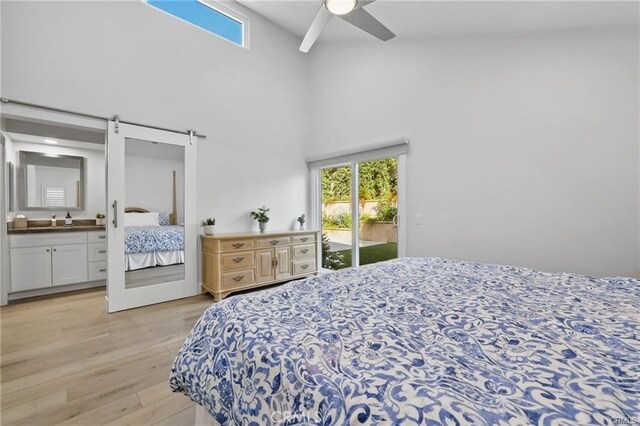 bedroom featuring a barn door, ceiling fan, connected bathroom, a high ceiling, and access to exterior