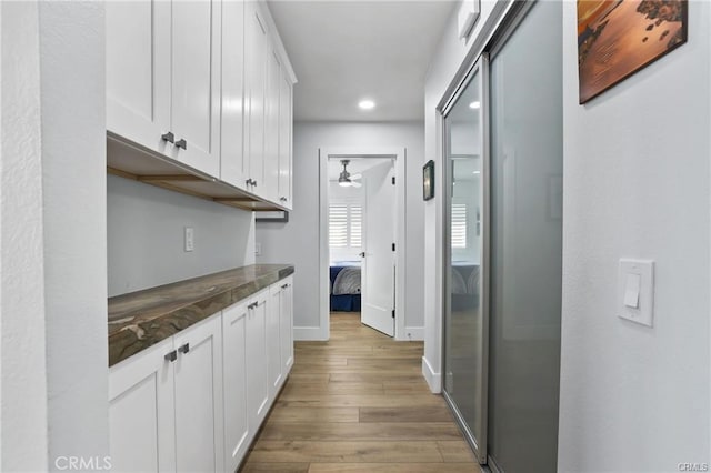 interior space with ceiling fan, white cabinetry, and light wood-type flooring