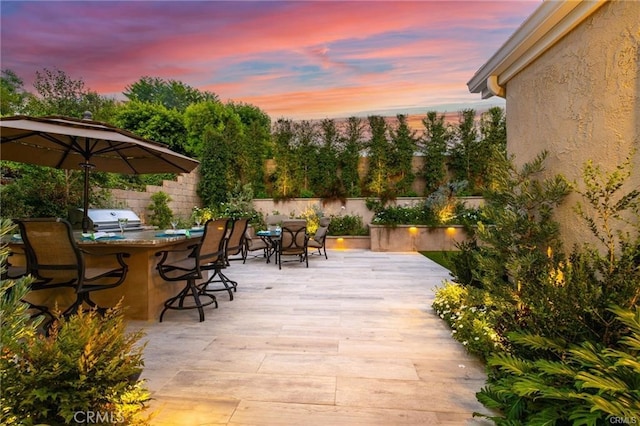 patio terrace at dusk with area for grilling and an outdoor bar