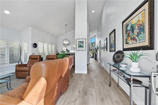 living room featuring light wood-type flooring, vaulted ceiling, and a notable chandelier