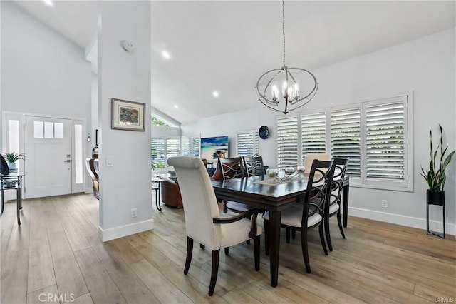 dining room with high vaulted ceiling, a notable chandelier, and light hardwood / wood-style flooring