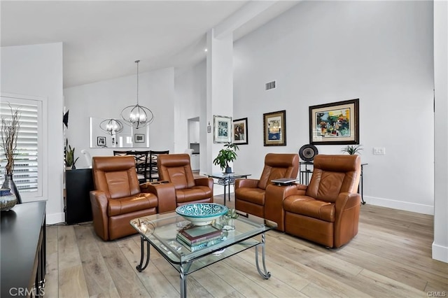 living room with high vaulted ceiling, light wood-type flooring, and a chandelier