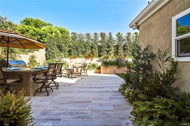 view of patio with exterior kitchen, a bar, and area for grilling