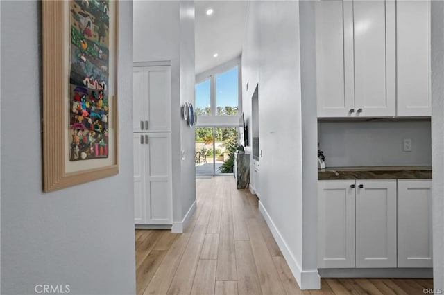 hall featuring a towering ceiling and light hardwood / wood-style flooring